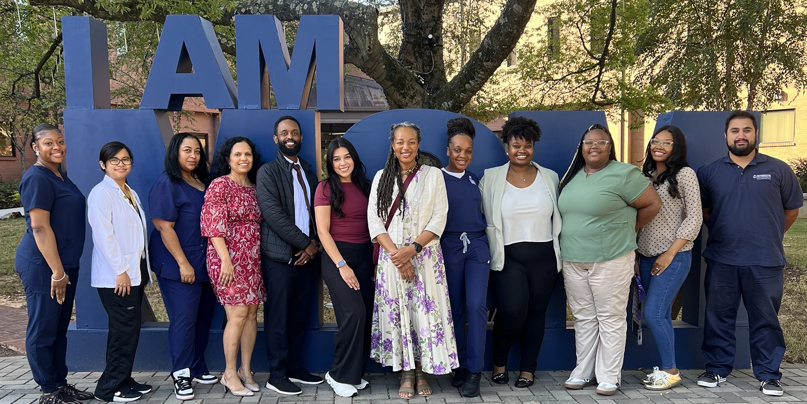 Twelve team members gather outside in front of an outdoor sculpture. The team works on RECOVER-AUTONOMIC at Morehouse School of Medicine in Atlanta, Georgia.