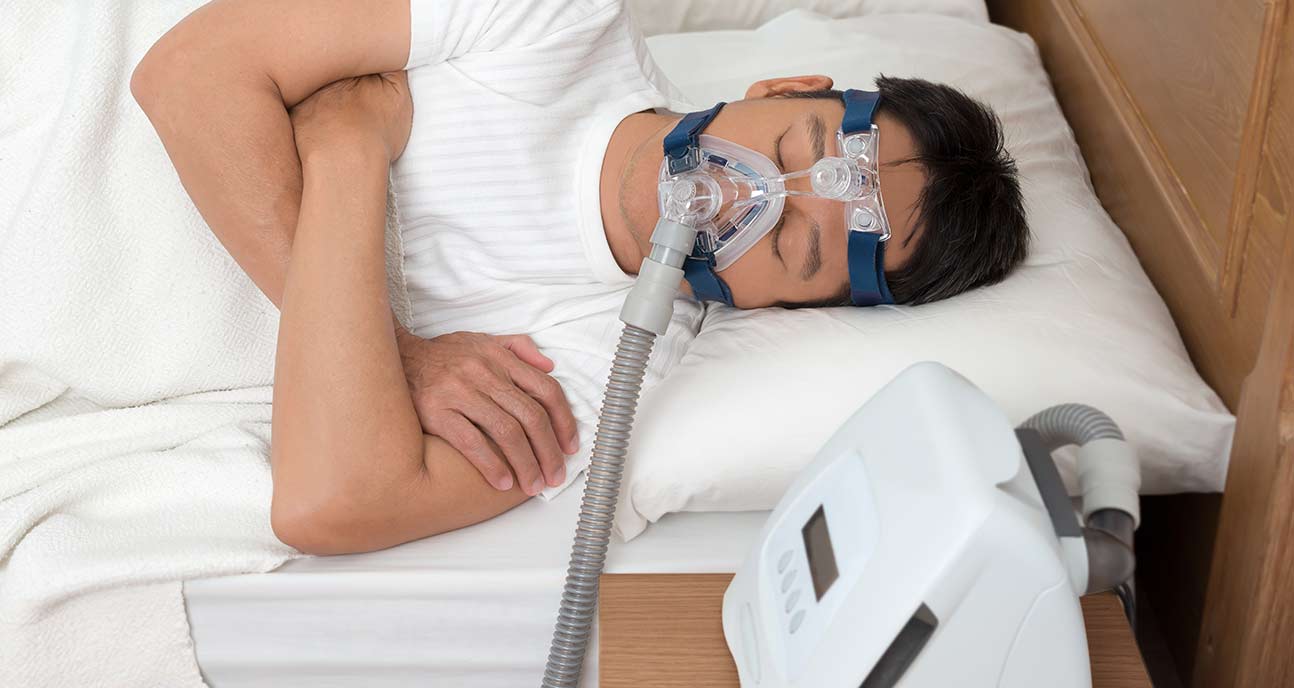 A person asleep wearing a CPAP machine.