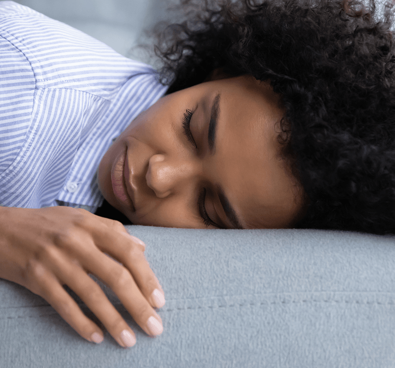 A person sleeping on their side with their head resting on a pillow and one hand extended in front of them.