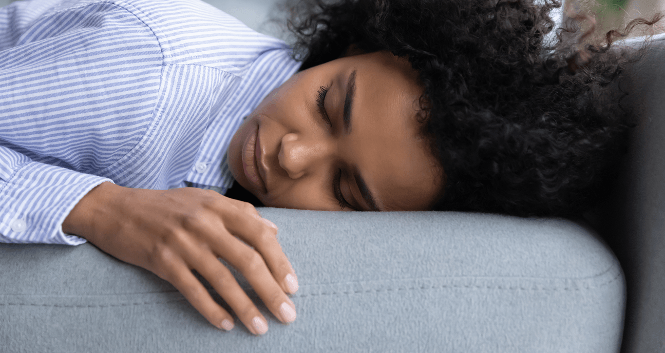 A person sleeping on their side with their head resting on a pillow and one hand extended in front of them.
