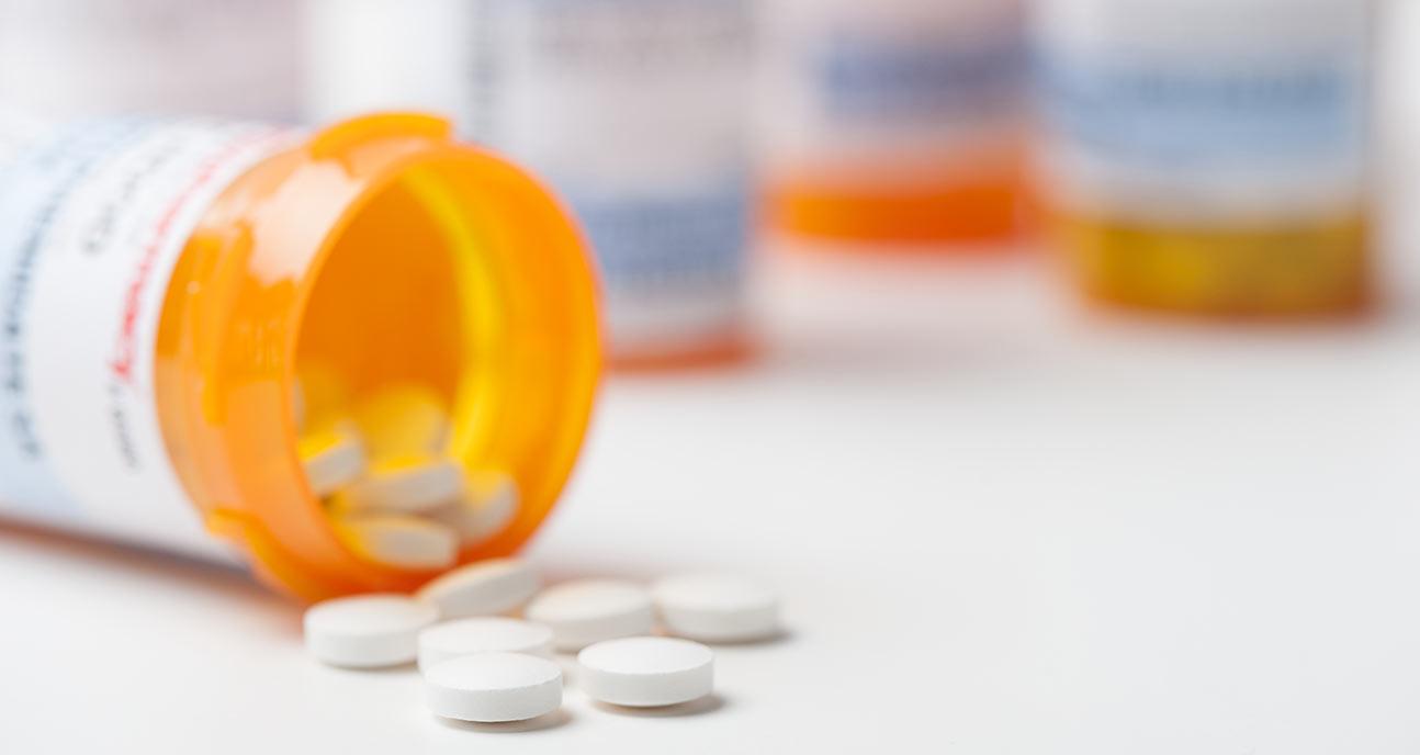 Orange medicine bottle on its side with white pills falling out.