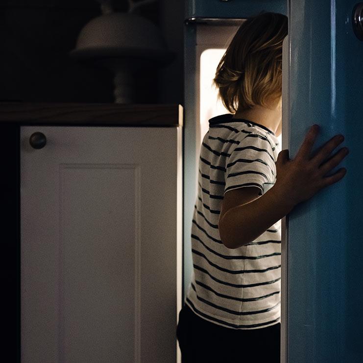 Young boy looks into empty refrigerator.