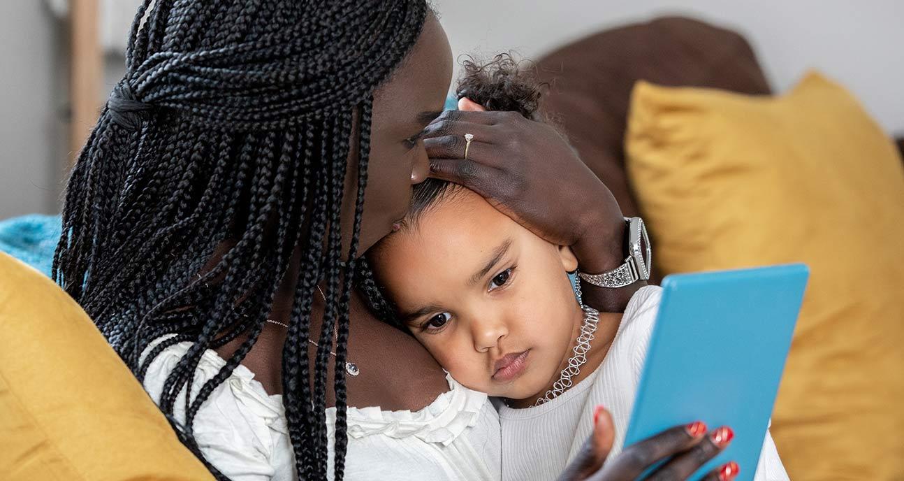 Mother holds toddler and kisses their head.