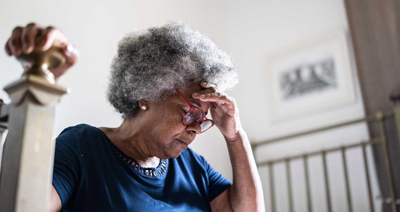 Older woman with hand on forehead looking stressed.